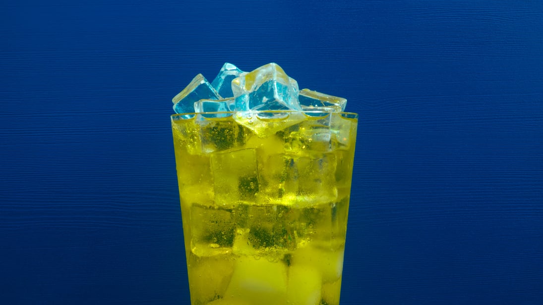 Inca Kola soda glass with ice on a blue background