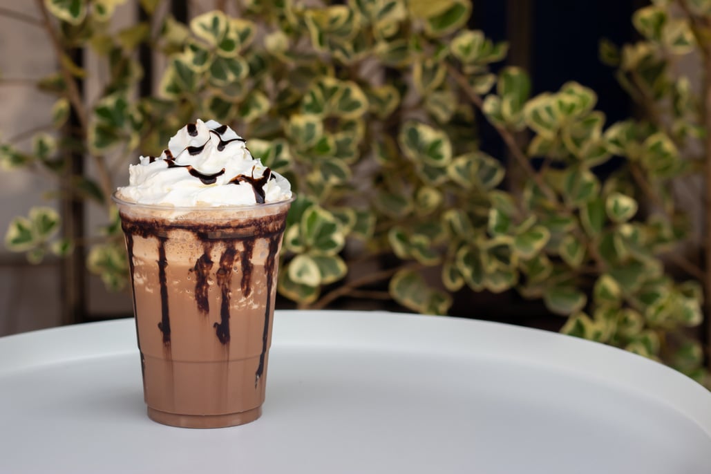 Mocha frappe in plastic cup. Served with whipping cream and chocolate sauce.